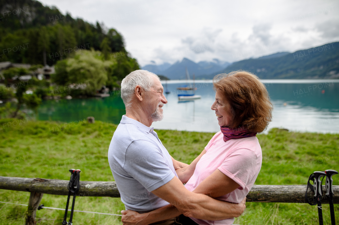 Portrait of elderly couple in love hiking together in mountains. Senior tourists embracing, going to kiss. Side view.