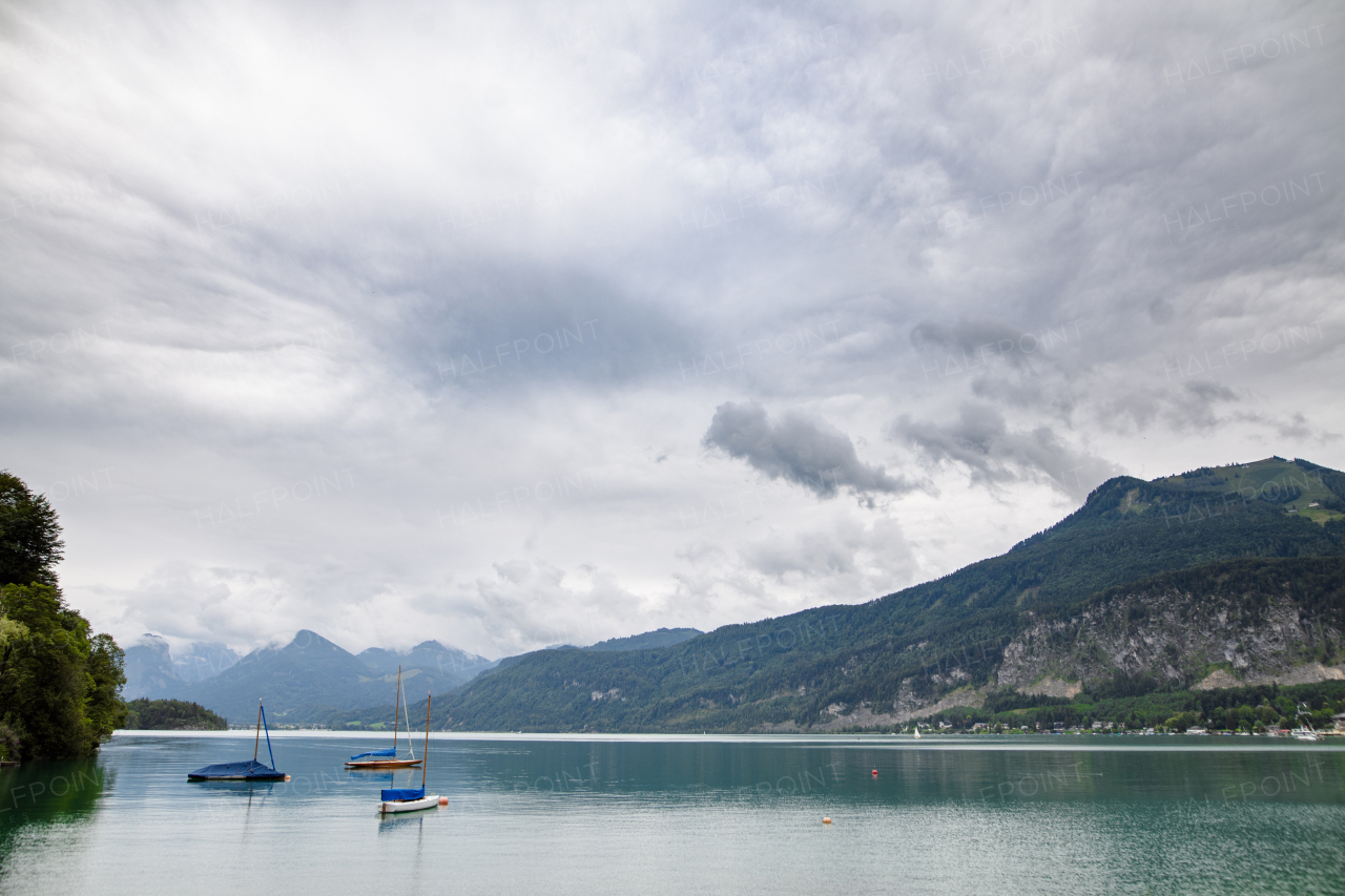 View of mountain lake with boats and beautiful nature, High Tatras, Slovakia. Landscape shot, spring cloudy day.