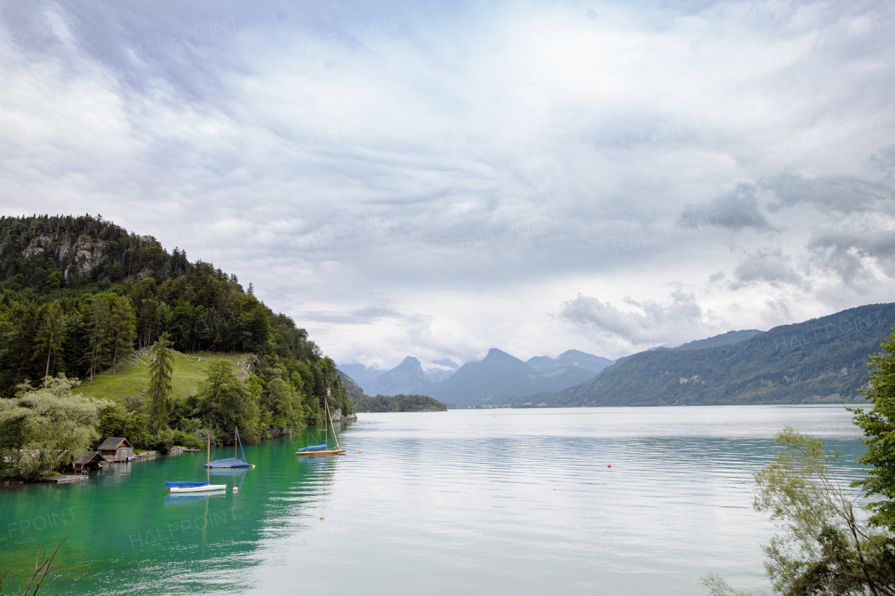 View of mountain lake with boats and beautiful nature, High Tatras, Slovakia. Landscape shot, spring cloudy day.