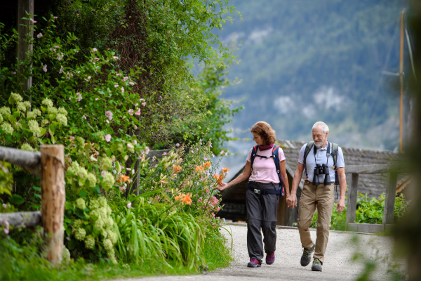 Active elderly couple on trip together, during early spring day. Senior tourists visiting, exploring new places. Sightseeing, holding hands.