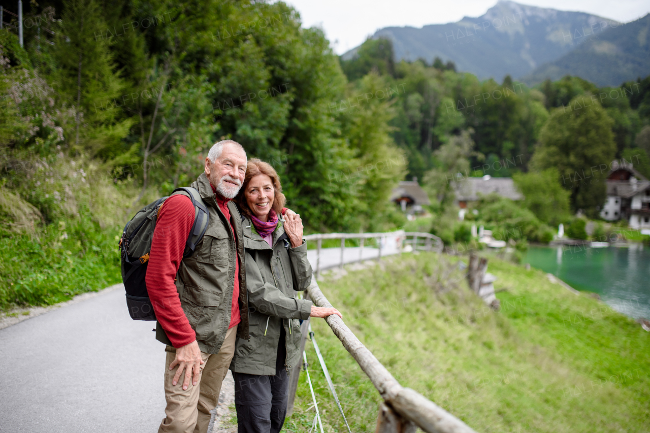 Active elderly couple hiking together in autumn mountains. Senior tourists enjoying view on lake.