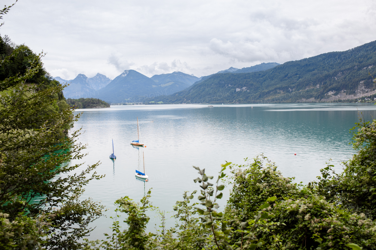 View of mountain lake with boats and beautiful nature, High Tatras, Slovakia. Landscape shot, spring cloudy day.