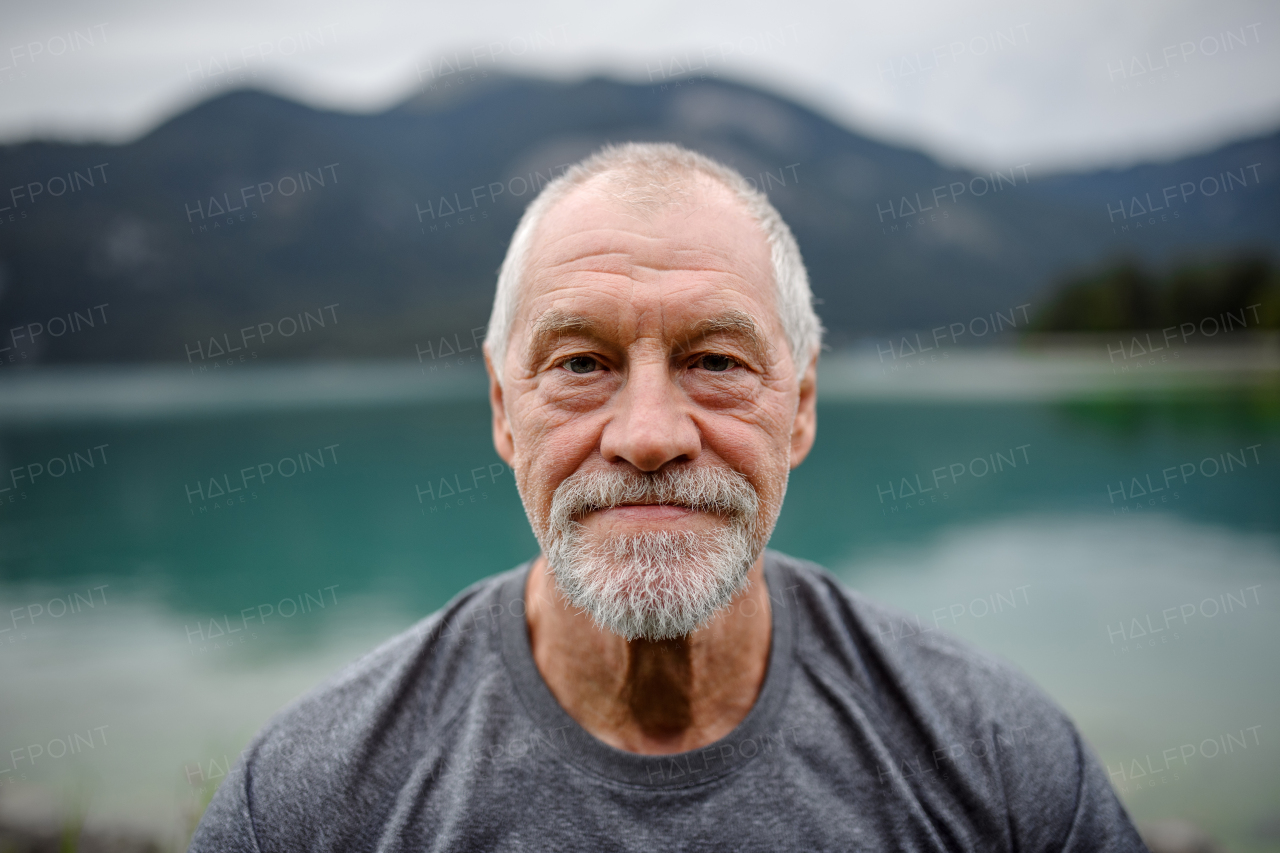 Portrait of active senior man resting after hiking in mountains. Thoughtful elderly man enjoying peaceful untouched nature.