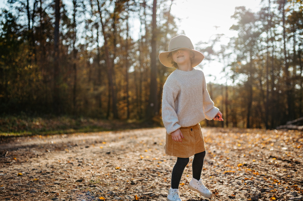 Portrait of cute girl with hat low on head in the middle autumn forest, having fun and laughing