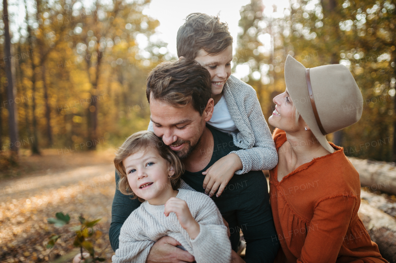 Portrait of family sitting in the middle autumn forest. Nuclear family spending weekend outdoors