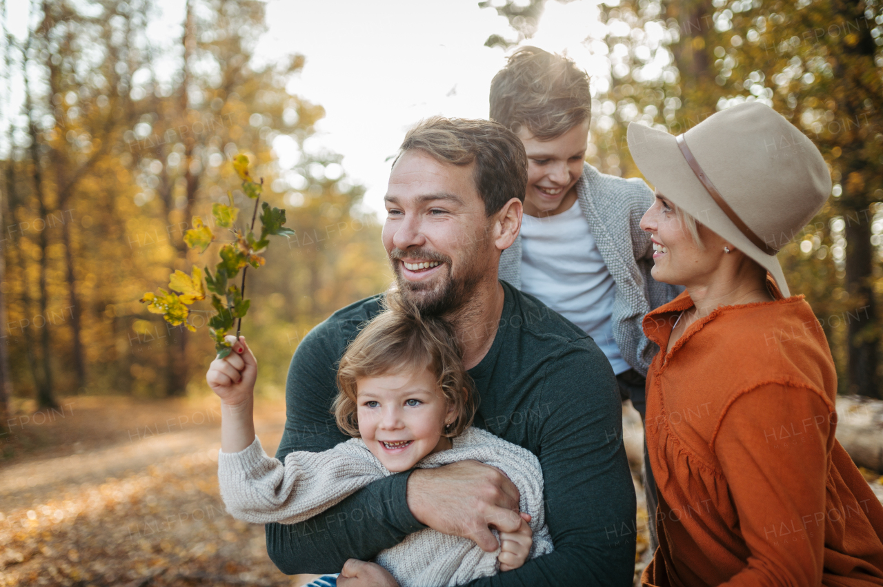 Portrait of family sitting in the middle autumn forest. Nuclear family spending weekend outdoors