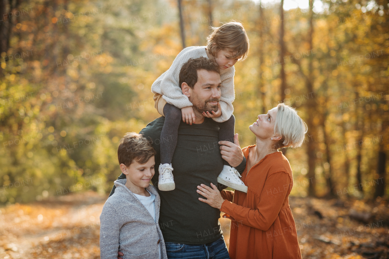 Young family with small children on walk in autumn forest. Father carrying daughter on his shoulders