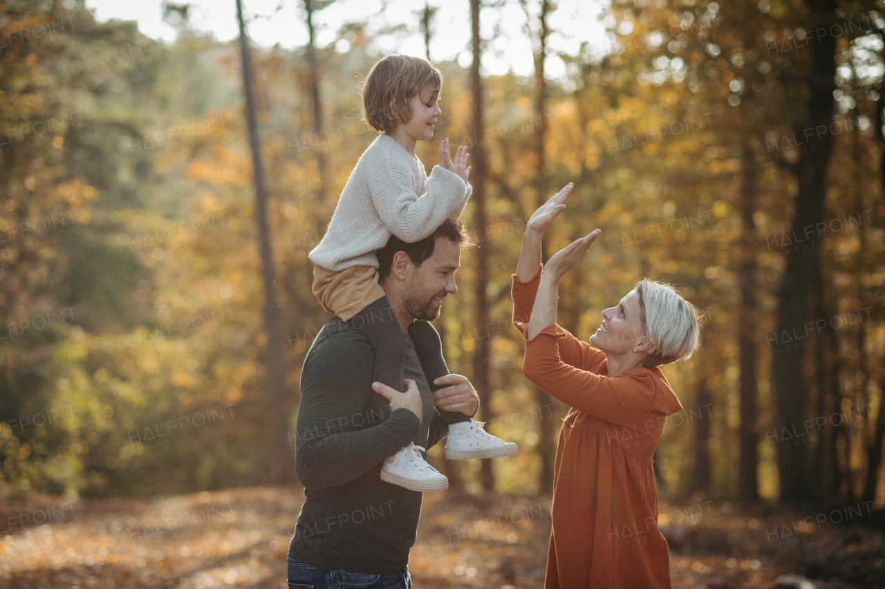 Young family with small children on walk in autumn forest. Father carrying daughter on his shoulders