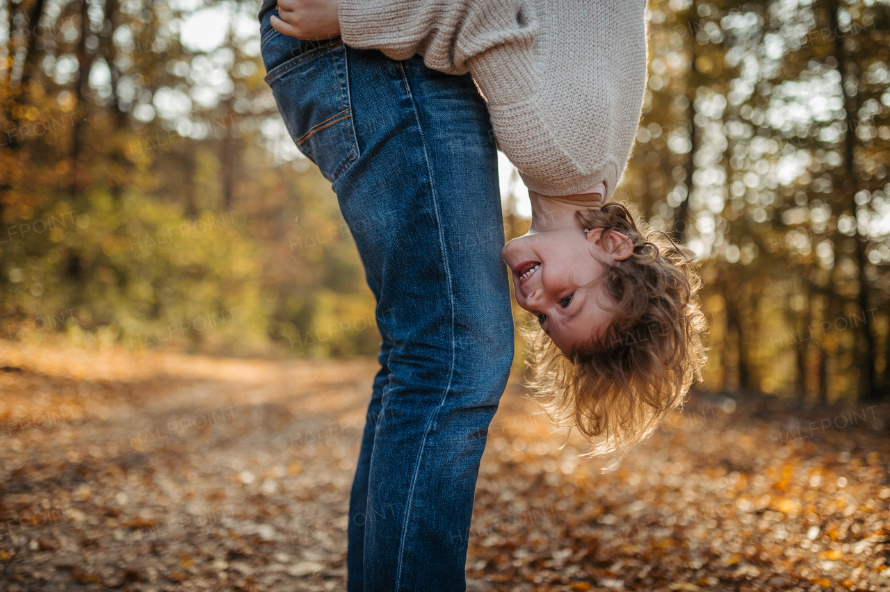 Father and girl are playful during walk in autumn forest. Dad and girl having fun outdoors