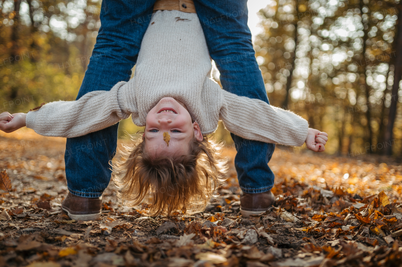 Father and girl are playful during walk in autumn forest. Dad and girl having fun outdoors