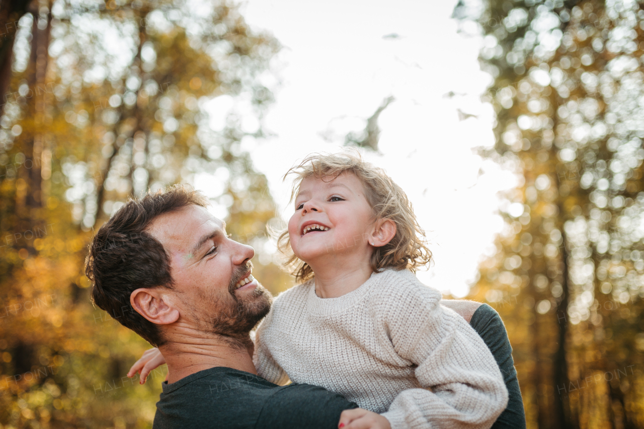 Father and girl during walk in autumn forest. Dad and girl having fun outdoors