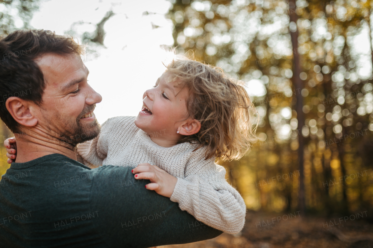 Father and girl during walk in autumn forest. Dad and girl having fun outdoors