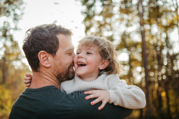 Father and girl during walk in autumn forest. Dad and girl having fun outdoors