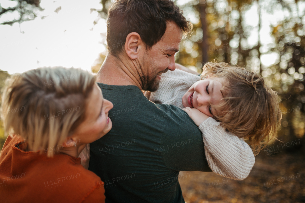 Parents and girl during walk in autumn forest. Girl having fun outdoors