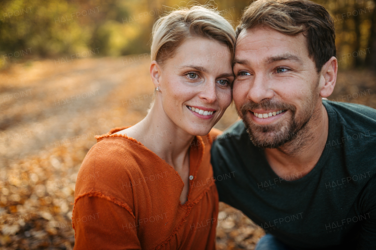 Couple in love on a walk in autumn forest. Husband and wife standing in the middle of forest, touching with foreheads