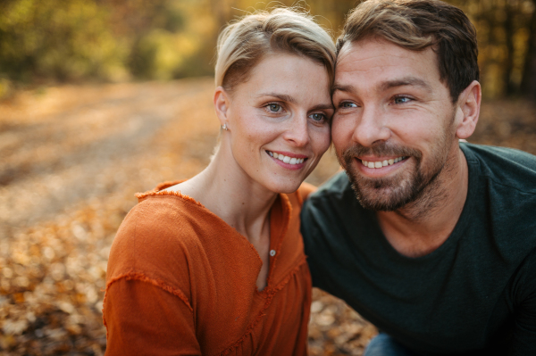 Couple in love on a walk in autumn forest. Husband and wife standing in the middle of forest, touching with foreheads