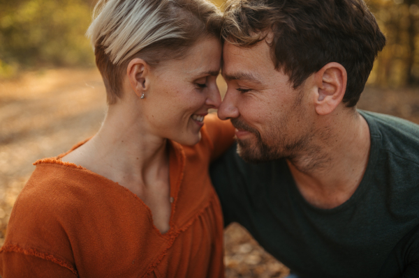 Couple in love on a walk in autumn forest. Husband and wife standing in the middle of forest, touching with foreheads