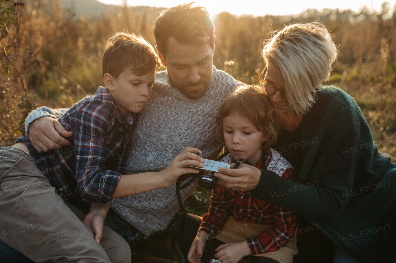 Portrait of family sitting in the middle of meadow. taking photos with vintage camera.