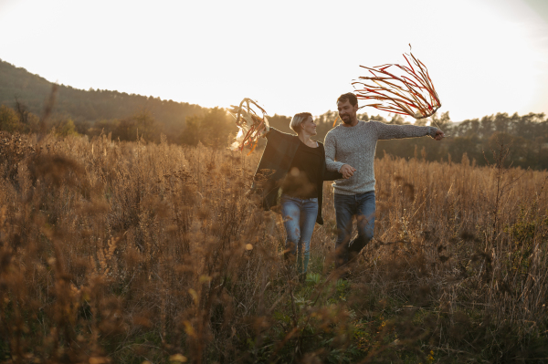 Couple in love on a walk in autumn forest. Husband holding wife hand, holding wreath with ribbons