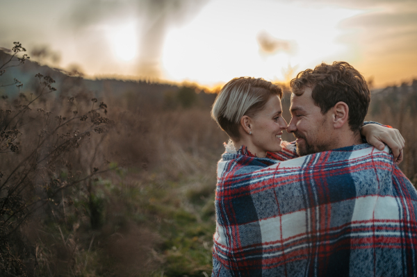 Couple in love on a walk in autumn forest. Husband and wife standing in the middle of meadow covered in warm blanket