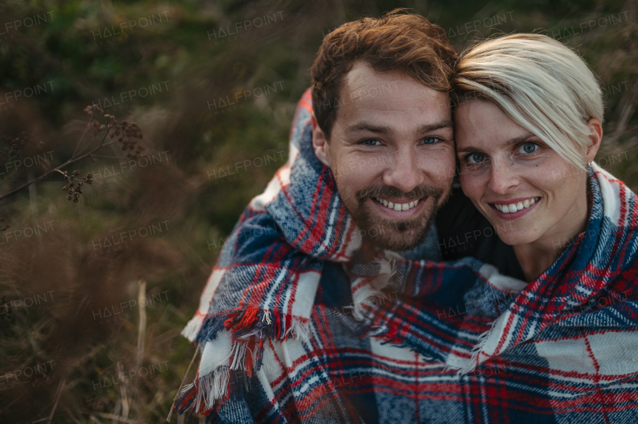 Couple in love on a walk in autumn forest. Husband and wife standing in the middle of meadow covered in warm blanket