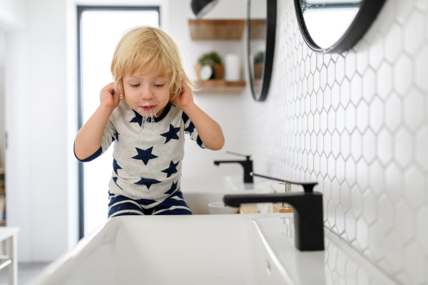 Boy spitting toothpaste after brushing his teeth. Morning routine for young boy before going to preschool.