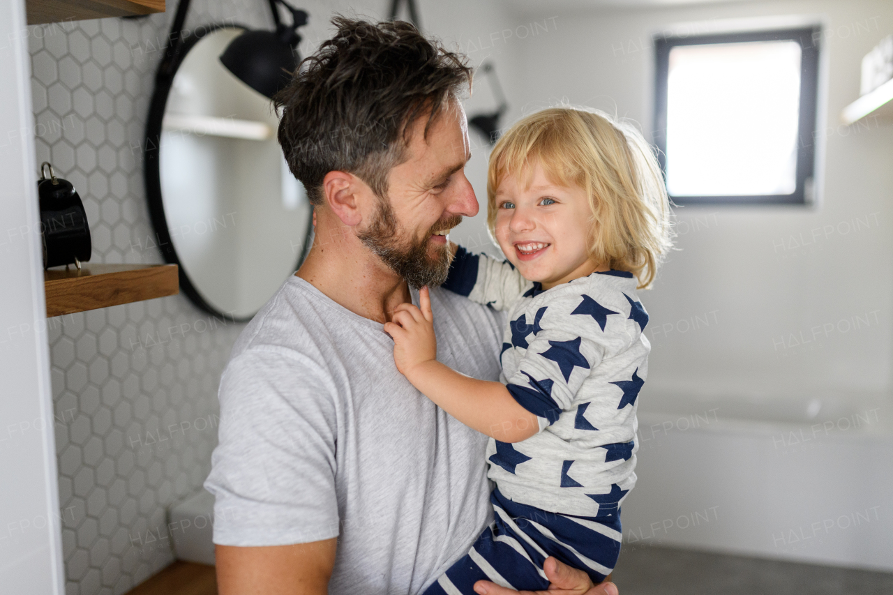 Father holding son in his arms, standing in bathroom. Morning routine for young boy before going to preschool.