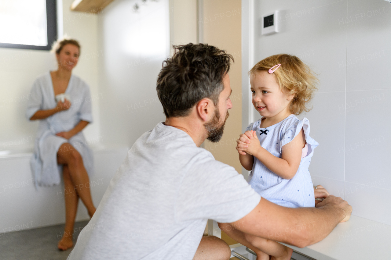 Father talking with cute little girl in bathroom, explaining morning bathroom routine. Small girl doing short morning prayer