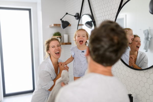 Parents and daughter having morning bathroom routine. brushing teeth and washing face, enjoying together time at home.