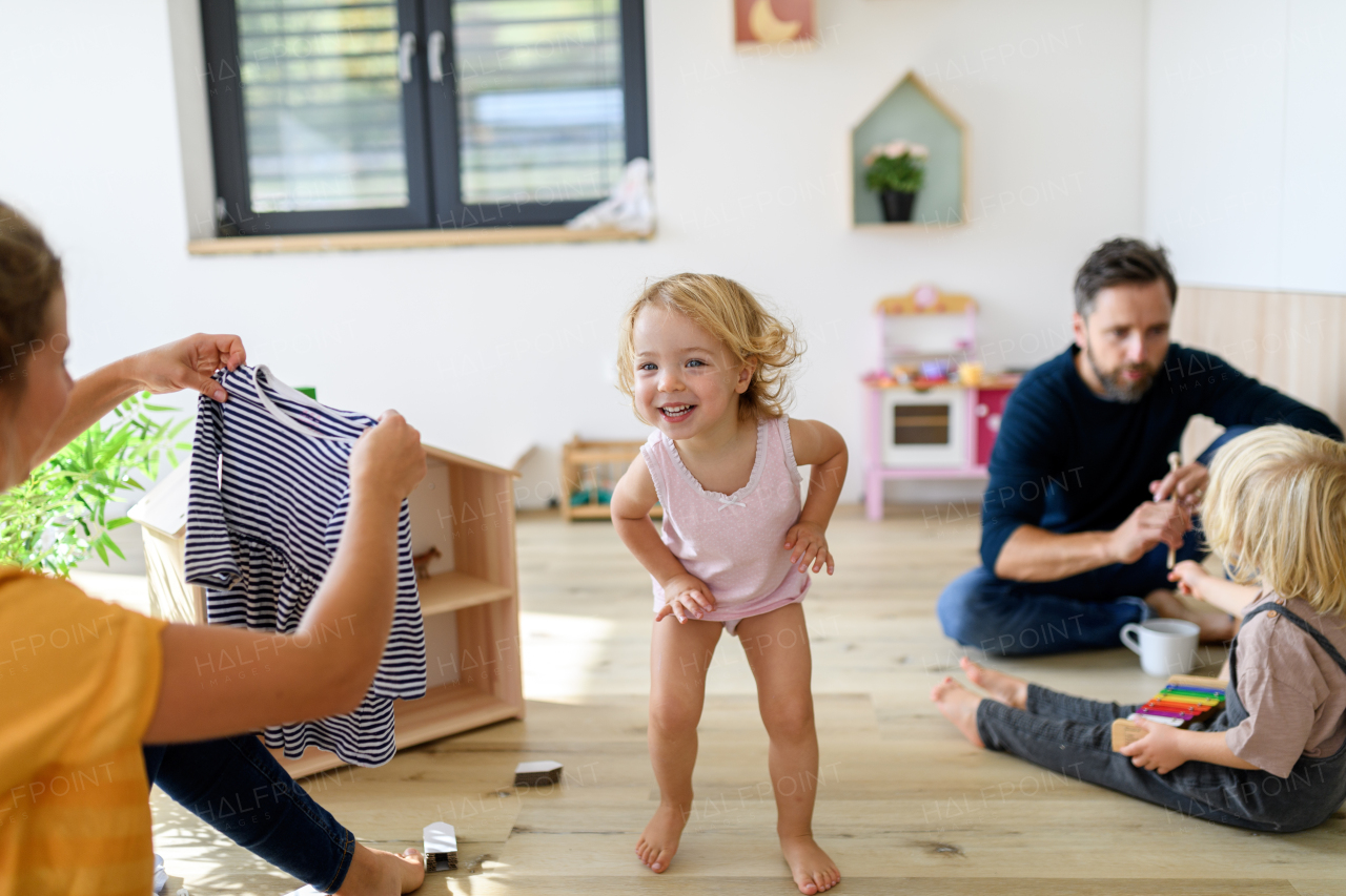 Young nuclear family playing with toys in a living room. Parents and children running, having fun, spending weekend day indoors.