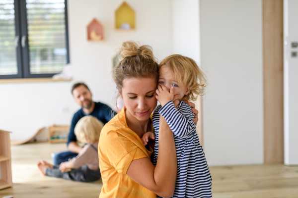 Little girl crying and screaming, mother holding her in arms, soothing her.