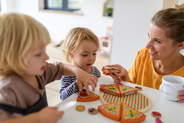 Young nuclear family playing with toys in a living room. Parents and children running, having fun, spending weekend day indoors.