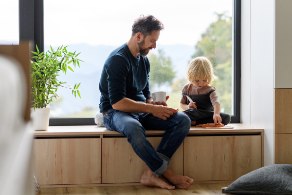 Dad and boy playing with wooden toys in the morning, father drinking morning cup of coffee. Handsome man eynjoying son's company, spending time with him. Father's day concept.