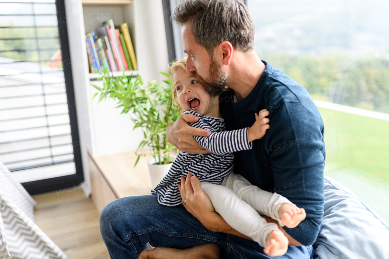 Father holding little daughter in arms, kissing her forehead. Dad enjoying fatherly moment. ather's day concept.