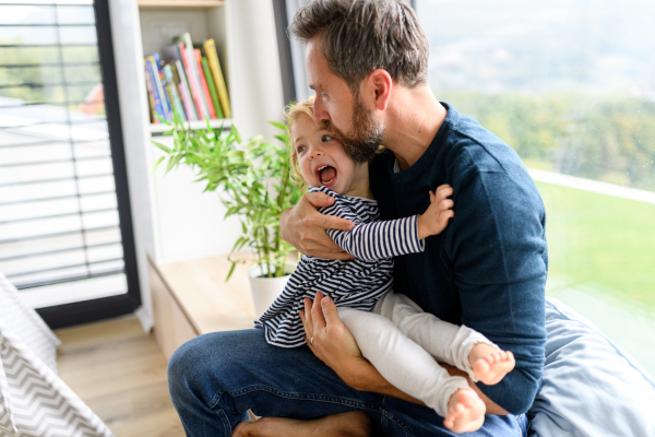 Father holding little daughter in arms, kissing her forehead. Dad enjoying fatherly moment. ather's day concept.