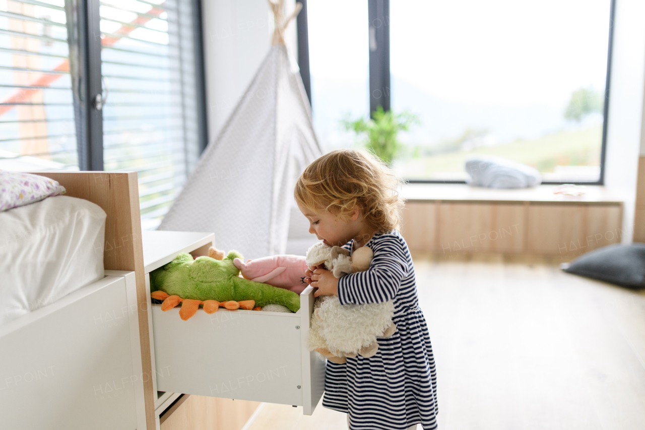 Cute small girl searching for plush toy in her room, copy space.