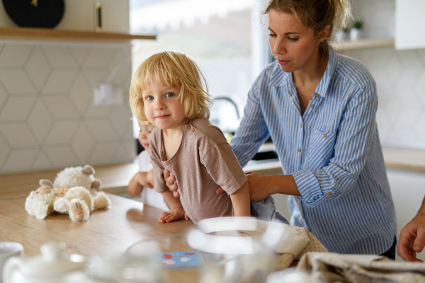 Mom and kids making pancakes together. Parent and children in kitchen, preparing pancake batter, spending weekend day indoors.