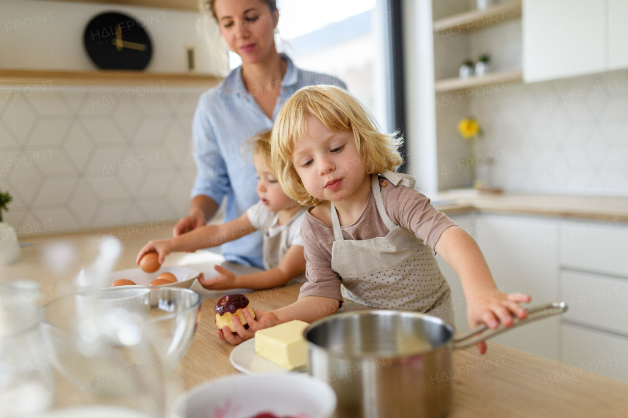 Nuclear family making pancakes together. Parents and children in kitchen, preparing pancake batter, spending weekend day indoors.