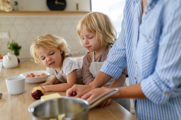 Mom and kids making pancakes together. Parent and children in kitchen, preparing pancake batter, spending weekend day indoors.