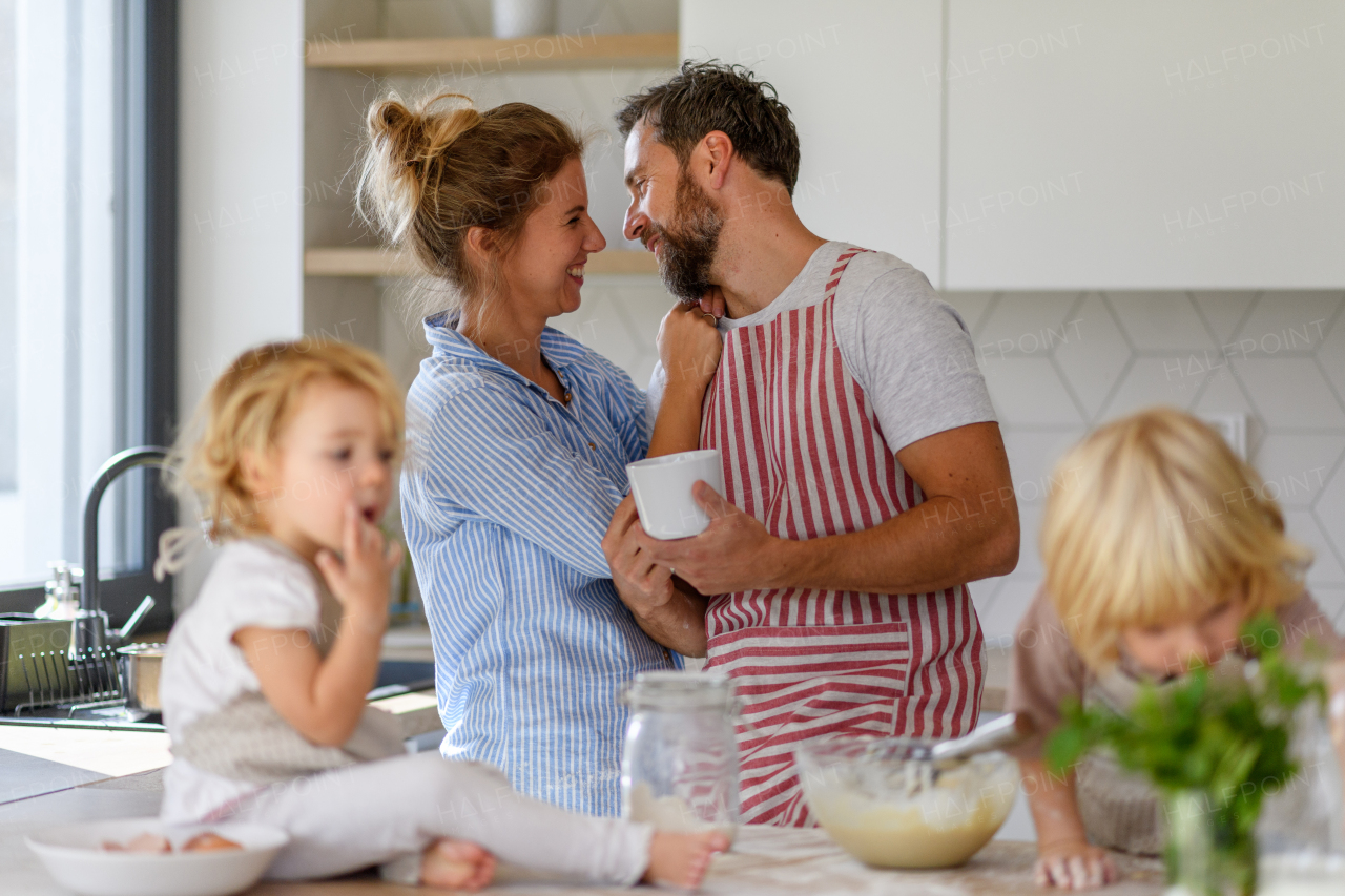 Nuclear family making pancakes together. Parents and children in kitchen, preparing pancake batter, spending weekend day indoors.