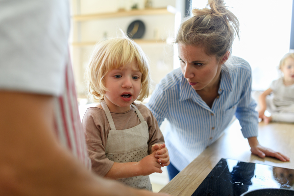 Young boy burn his finger while helping parents in kitchen. Mother soothing him.