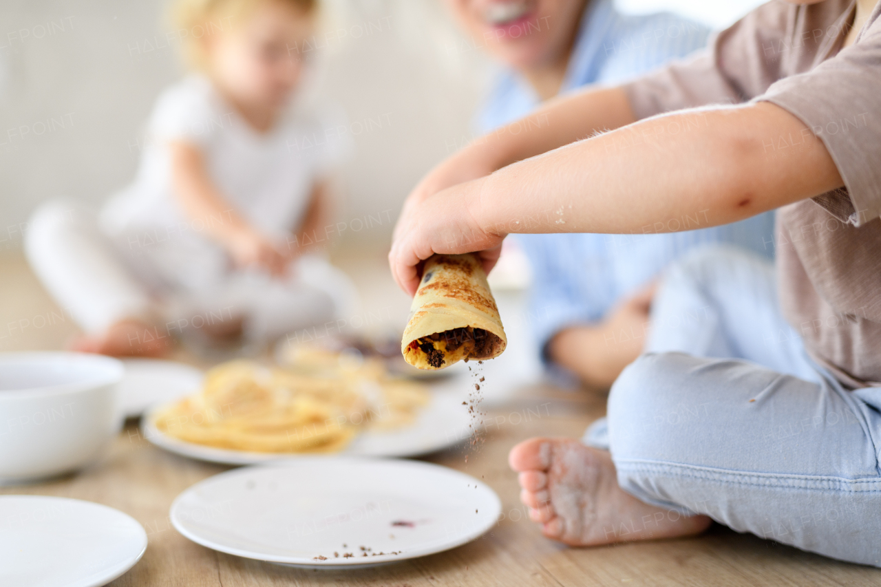 Family eating pancakes together, morning in kitchen. Mom and children spending weekend day indoors.