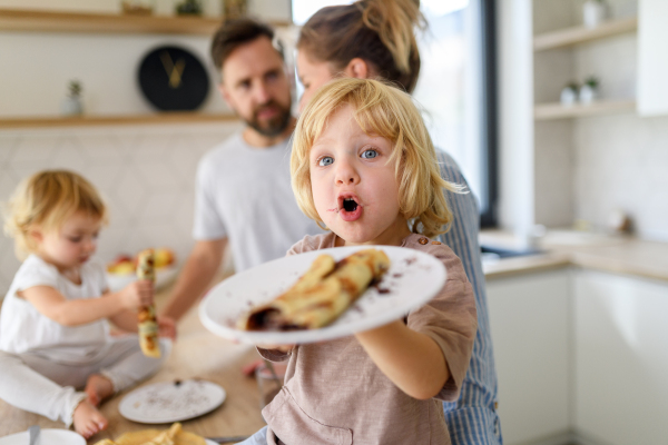 Nuclear family making pancakes together. Parents and children in kitchen, spending weekend day indoors.