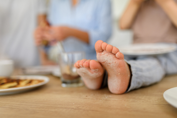 Dirty feet after making pancakes in kitchen. Family eating pancakes for breakfast. Parents and children spending weekend day indoors.