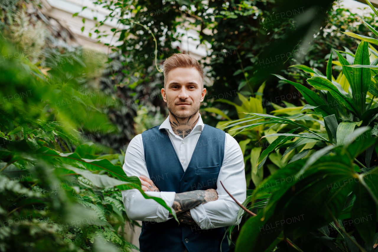 businessman standing in botanical garden, in the middle of lush green foliage, looking at camera. Concept of business corporate social responsibility and ESG.