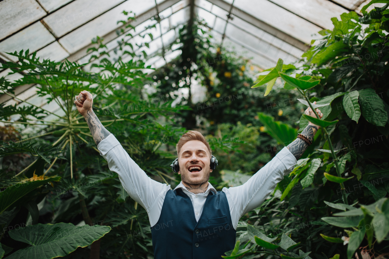 businessman standing in botanical garden, in the middle of lush green foliage, arms in the air, success. Concept of corporate social responsibility and ESG.