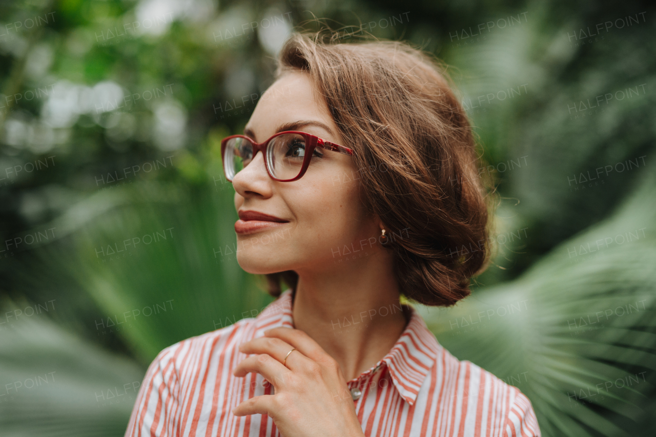 Woman standing in botanical garden, in the middle of lush green foliage.