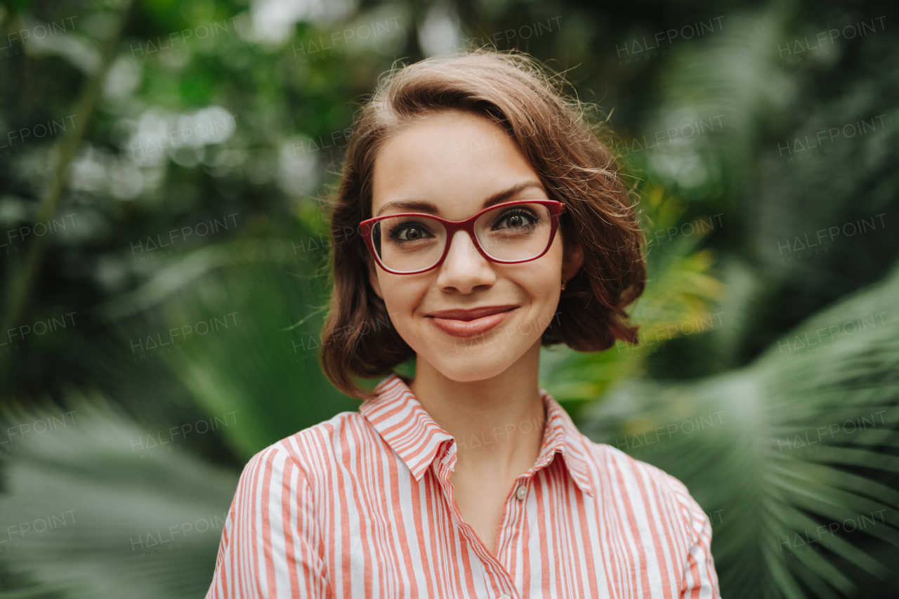 Woman standing in botanical garden, in the middle of lush green foliage.