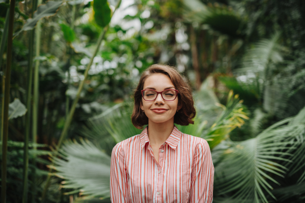 Woman standing in botanical garden, in the middle of lush green foliage.