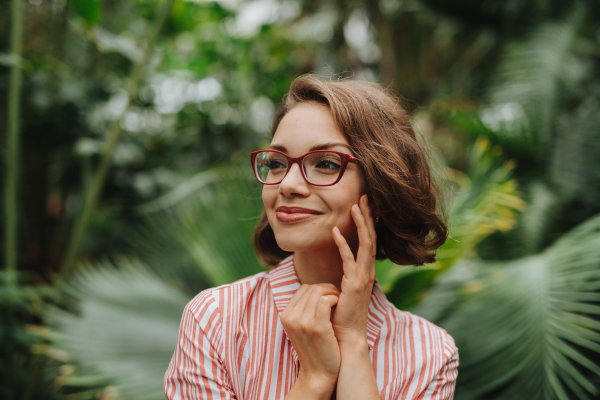 Woman standing in botanical garden, in the middle of lush green foliage.